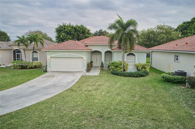 mediterranean / spanish-style home with a garage, concrete driveway, a tiled roof, a front lawn, and stucco siding