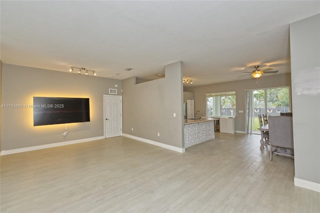 unfurnished living room featuring a textured ceiling, visible vents, light wood-style flooring, and baseboards