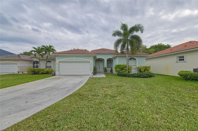 mediterranean / spanish home with stucco siding, an attached garage, driveway, a tiled roof, and a front lawn