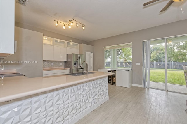 kitchen with light wood finished floors, beverage cooler, white cabinets, light countertops, and stainless steel refrigerator with ice dispenser