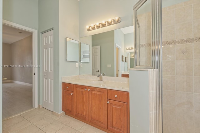 full bath with a tile shower, tile patterned flooring, vanity, and baseboards