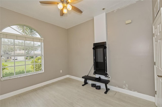 workout area with light wood-style floors, a ceiling fan, baseboards, and a wealth of natural light