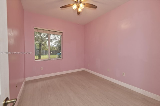 spare room with ceiling fan, light wood-type flooring, and baseboards