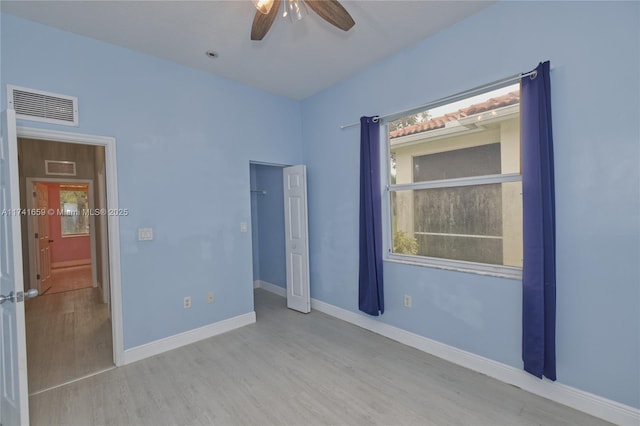 unfurnished bedroom with baseboards, multiple windows, visible vents, and wood finished floors