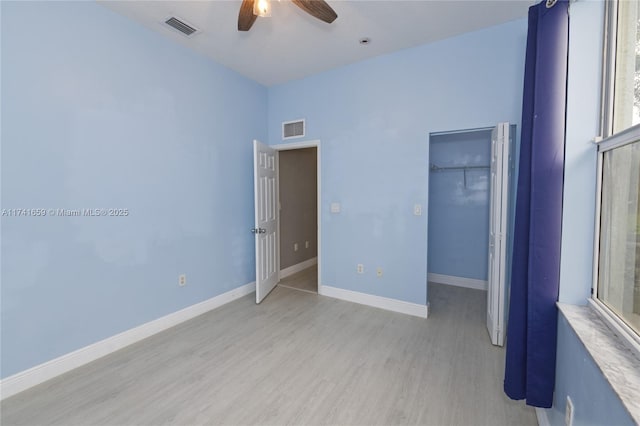 unfurnished bedroom featuring a spacious closet, light wood-type flooring, visible vents, and baseboards