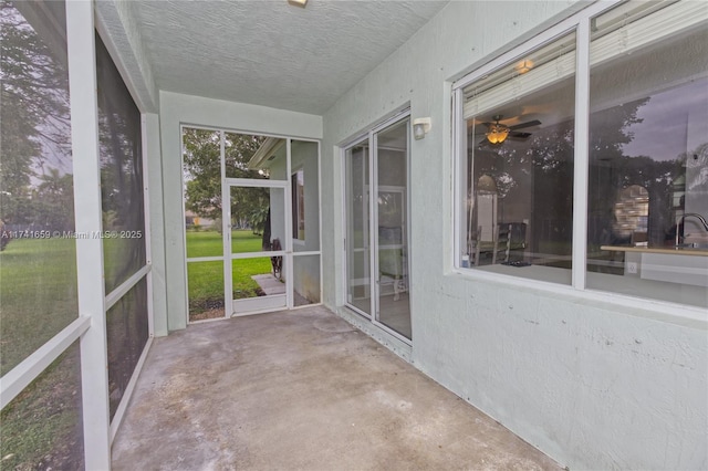 unfurnished sunroom featuring a ceiling fan