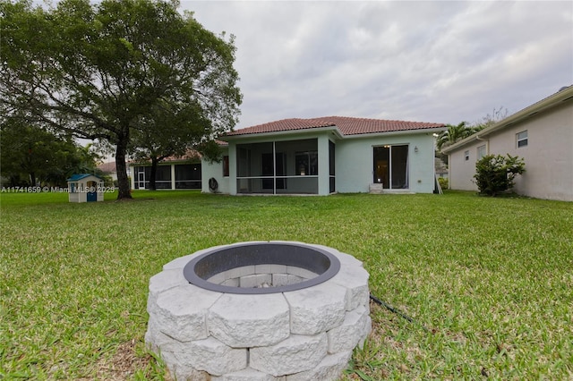 back of house featuring a fire pit, a tile roof, a sunroom, a lawn, and stucco siding