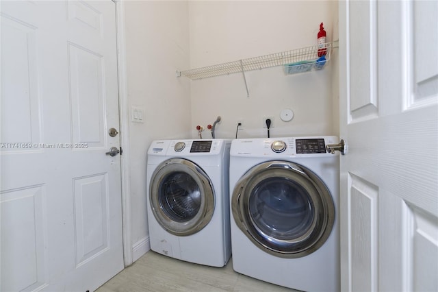 laundry room featuring laundry area, washing machine and dryer, and light wood-style flooring