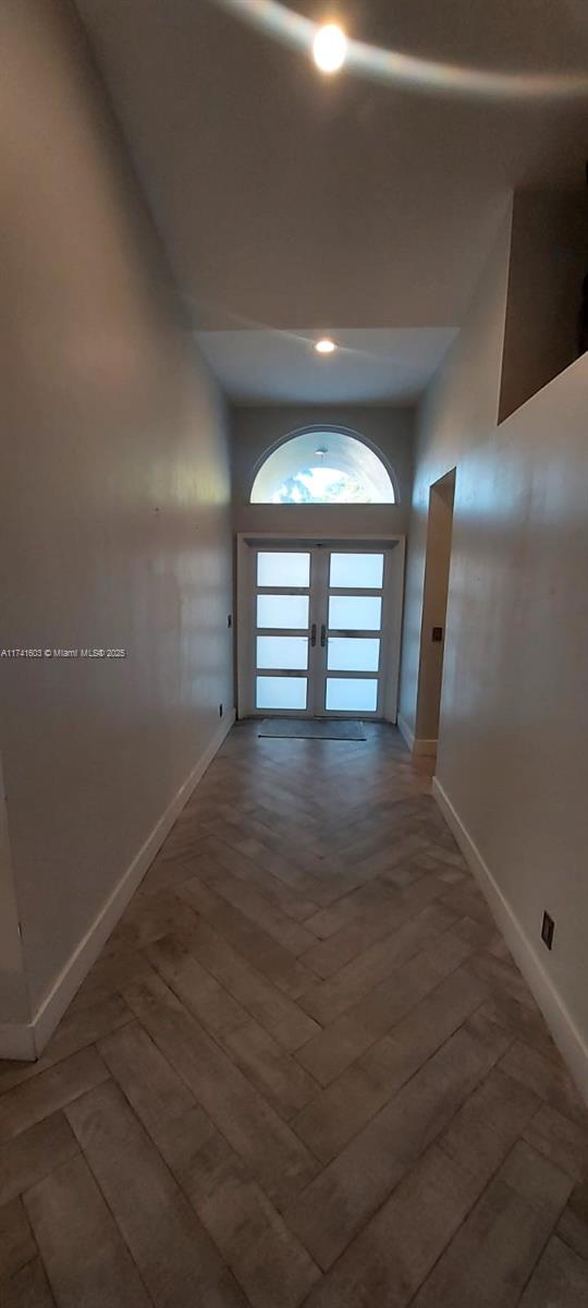 corridor with hardwood / wood-style flooring and french doors