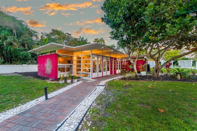 view of front of house with a front yard, a sunroom, and fence