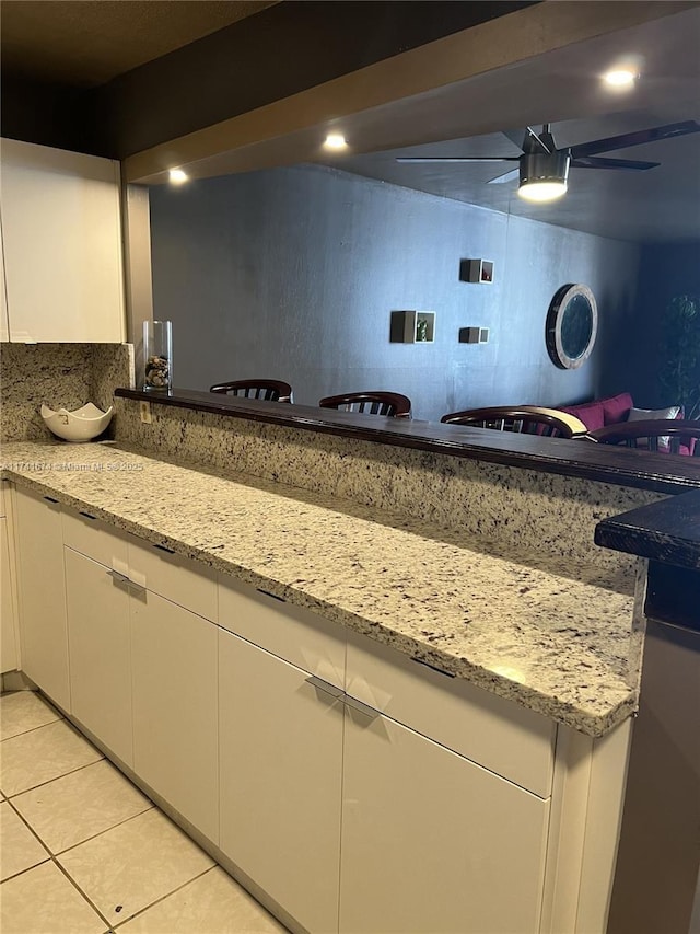 kitchen with light stone counters, white cabinets, and light tile patterned flooring