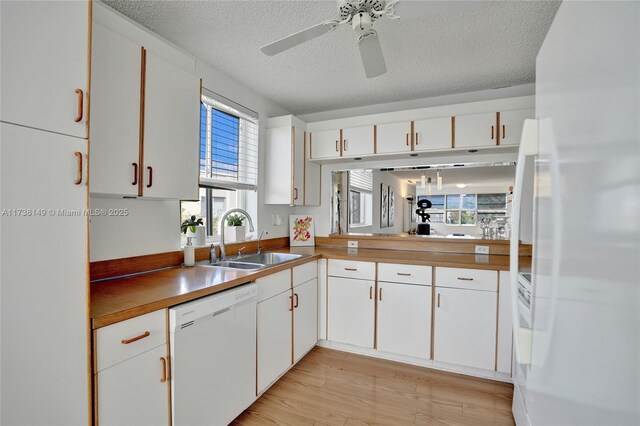7368 Devon Dr Unit 301, Tamarac, FL 33321 - kitchen with white cabinetry, sink, light wood-type flooring, white appliances, and a textured ceiling