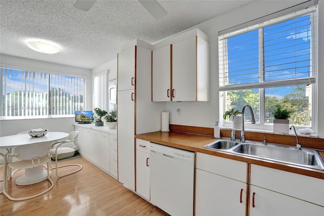7368 Devon Dr Unit 301, Tamarac, FL 33321 - kitchen featuring sink, a textured ceiling, white dishwasher, light hardwood / wood-style floors, and white cabinets
