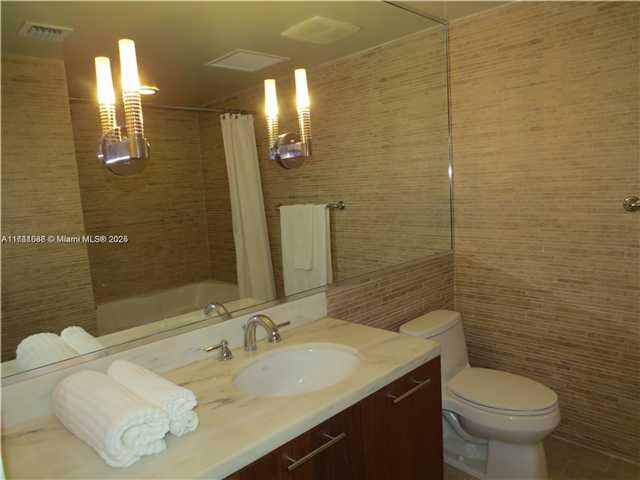 full bathroom featuring vanity, tile walls, shower / tub combo, and toilet