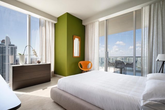 bedroom with access to exterior, a view of city, light carpet, and baseboards