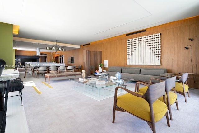 carpeted living area featuring wood walls