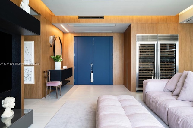 living room featuring beverage cooler, wood walls, and visible vents