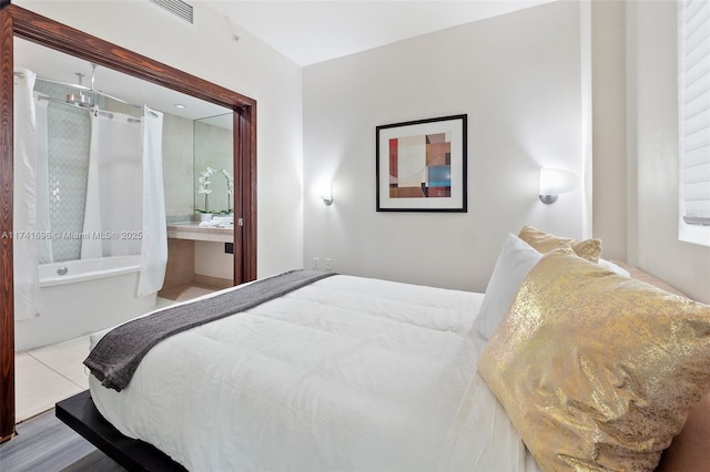 bedroom with connected bathroom and tile patterned floors