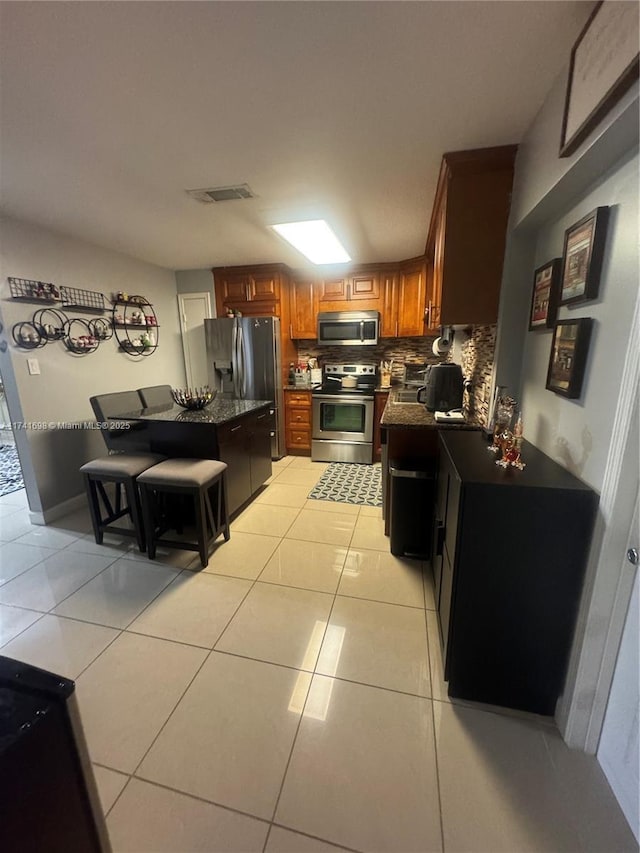 kitchen with a kitchen breakfast bar, light tile patterned floors, stainless steel appliances, and decorative backsplash