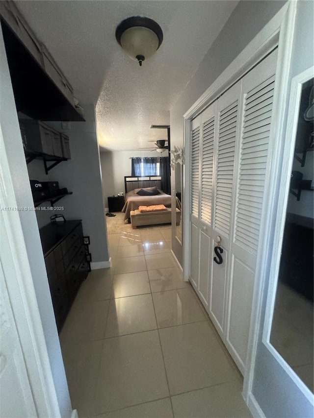 hallway with a textured ceiling and light tile patterned floors