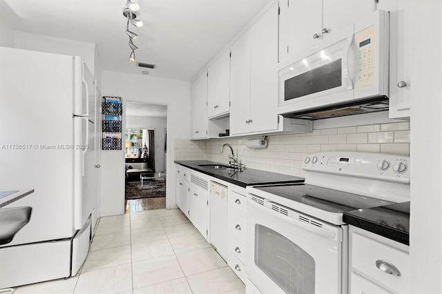 kitchen featuring white cabinetry, sink, backsplash, light tile patterned floors, and white appliances