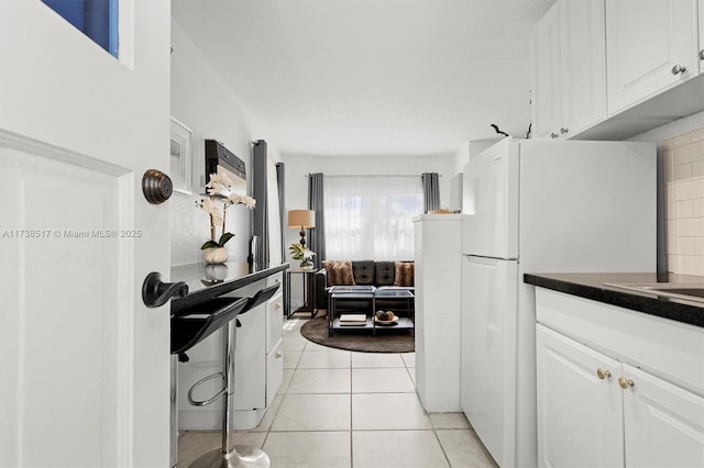 kitchen with backsplash, light tile patterned floors, and white cabinets