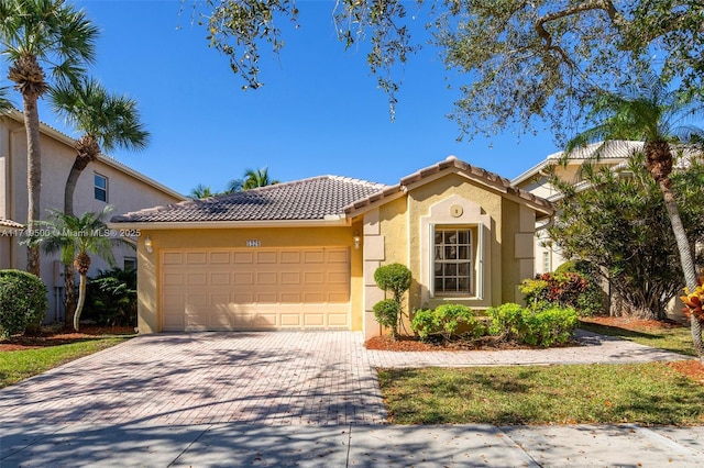 mediterranean / spanish home featuring a garage, a tiled roof, decorative driveway, and stucco siding