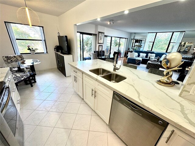 3850 Washington St Unit 317, Hollywood, FL 33021 - kitchen with sink, stainless steel dishwasher, pendant lighting, light stone countertops, and white cabinets