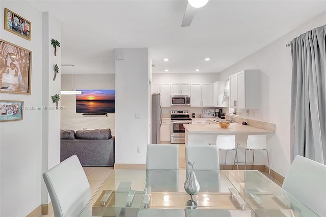 kitchen featuring sink, a breakfast bar area, white cabinetry, stainless steel appliances, and kitchen peninsula