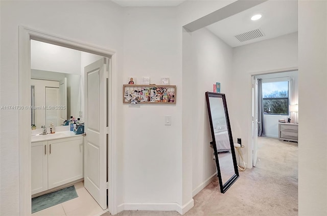 hallway featuring light carpet and sink