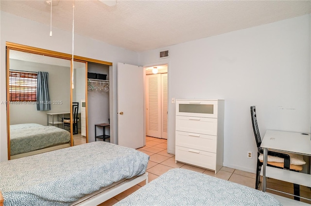 bedroom featuring light tile patterned flooring, a textured ceiling, and a closet