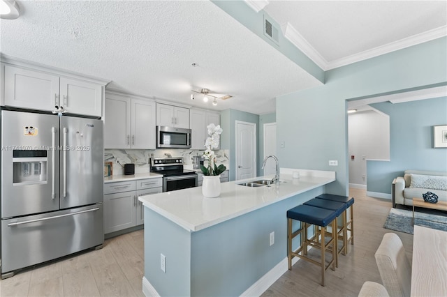 kitchen featuring sink, light hardwood / wood-style flooring, stainless steel appliances, a kitchen breakfast bar, and decorative backsplash