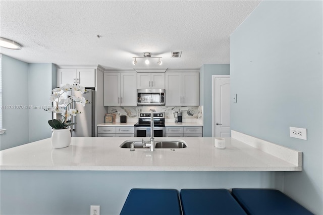 kitchen featuring tasteful backsplash, appliances with stainless steel finishes, sink, and a kitchen bar