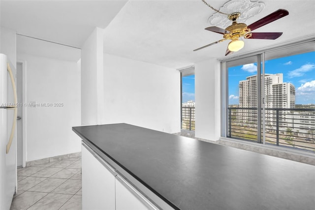 kitchen featuring white refrigerator, light tile patterned floors, white cabinets, and ceiling fan