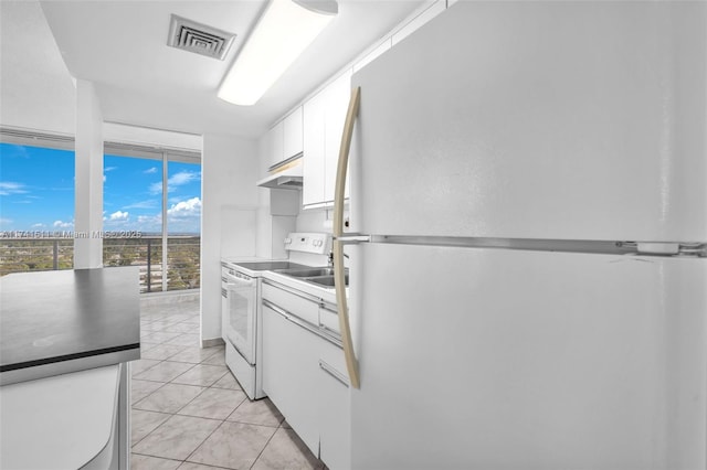 kitchen featuring light tile patterned floors, white appliances, floor to ceiling windows, and white cabinets