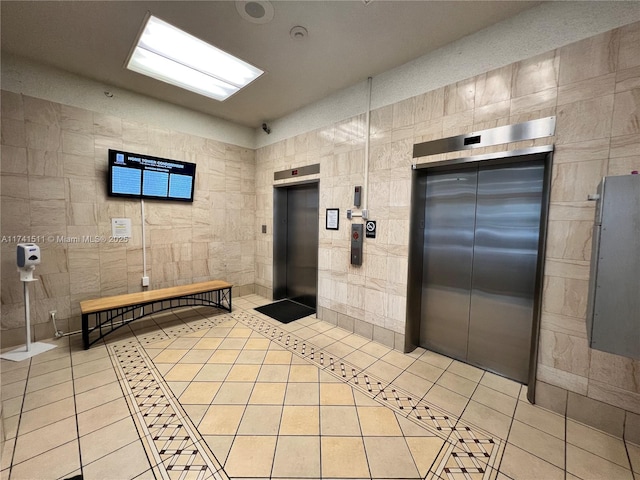 bathroom featuring tile patterned flooring, tile walls, and elevator