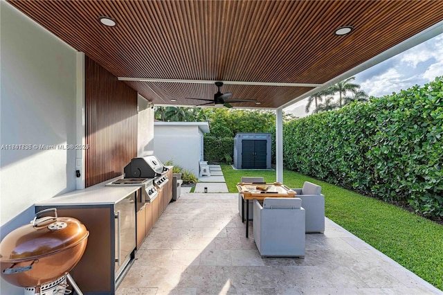 view of patio / terrace with area for grilling, ceiling fan, and a storage unit