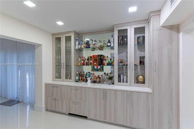 bar featuring light tile patterned floors and light brown cabinetry