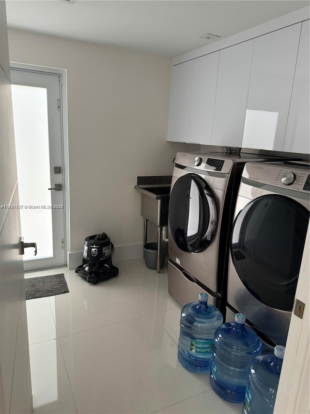 laundry area featuring separate washer and dryer, tile patterned floors, and cabinets