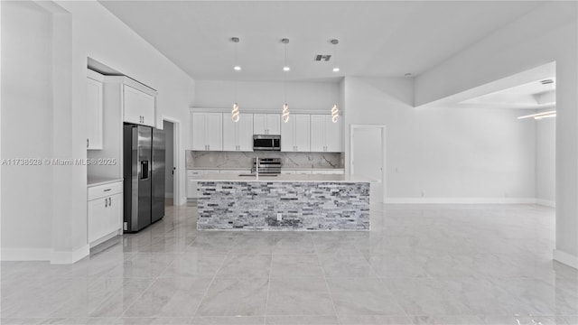 kitchen with white cabinetry, tasteful backsplash, hanging light fixtures, appliances with stainless steel finishes, and a kitchen island with sink