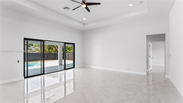 unfurnished room with a raised ceiling, a high ceiling, and ceiling fan