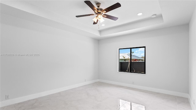 spare room with a raised ceiling and ceiling fan