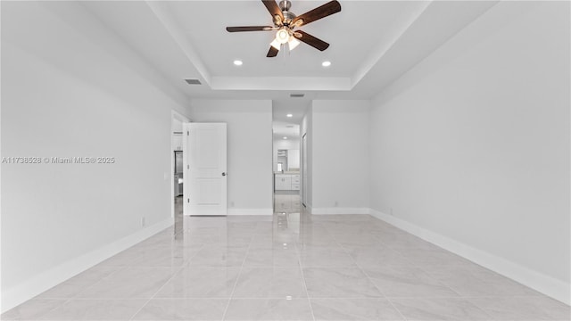 empty room featuring ceiling fan and a tray ceiling