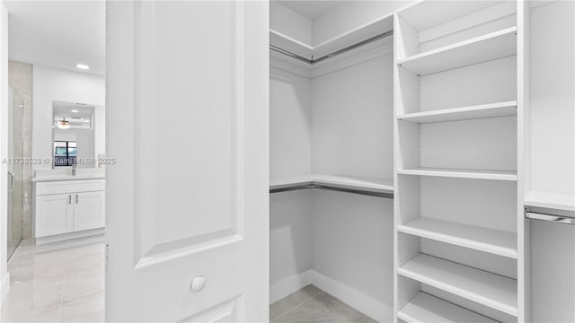 spacious closet with light tile patterned floors and ceiling fan