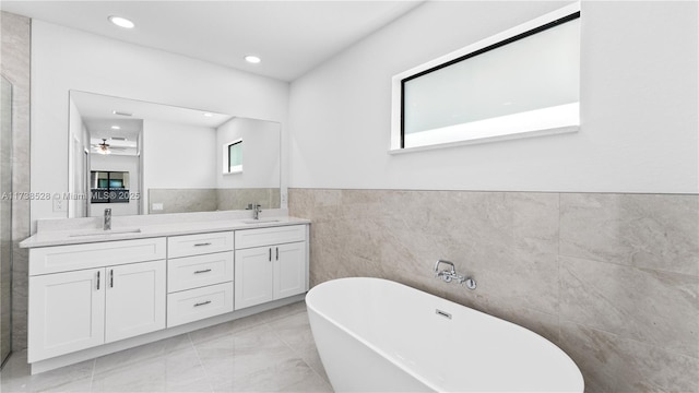 bathroom featuring vanity, a tub, tile walls, and ceiling fan