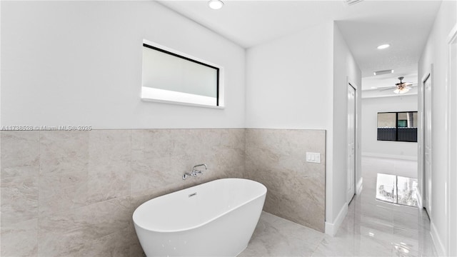 bathroom with a tub to relax in and tile walls