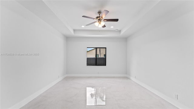 spare room featuring a raised ceiling and ceiling fan