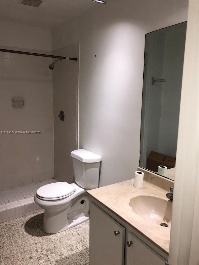 bathroom with vanity, tiled shower, and toilet