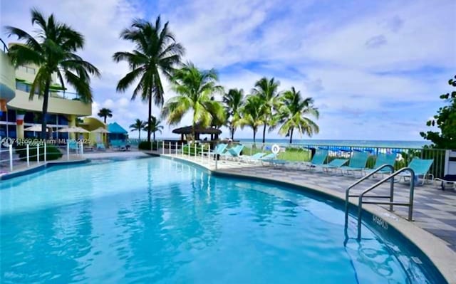 view of swimming pool with a water view and a patio area