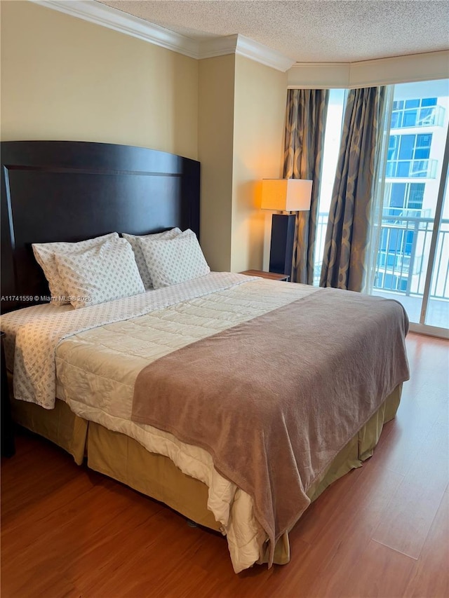 bedroom with crown molding, access to exterior, hardwood / wood-style floors, and a textured ceiling